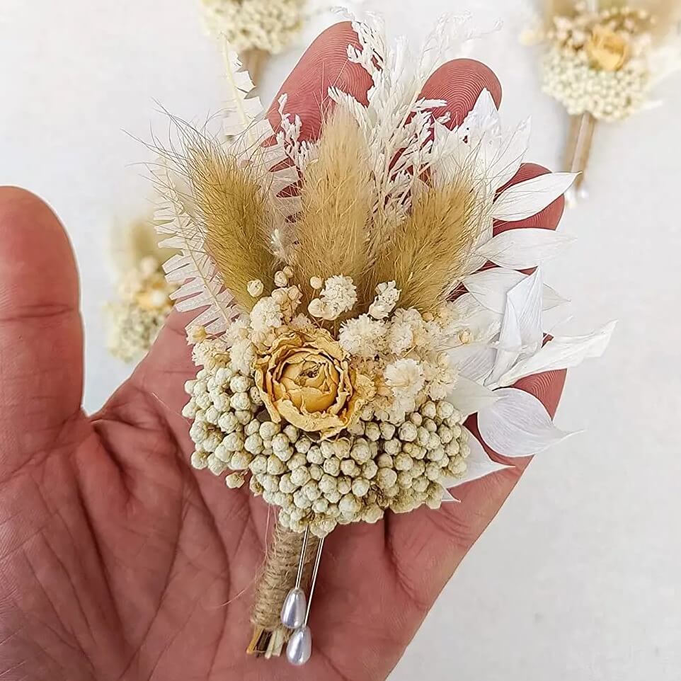 boutonnière en fleurs séchées beige dans une main